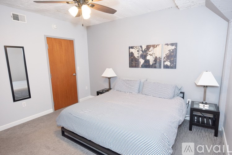 A bedroom with a bed, two lamps, and a ceiling fan.