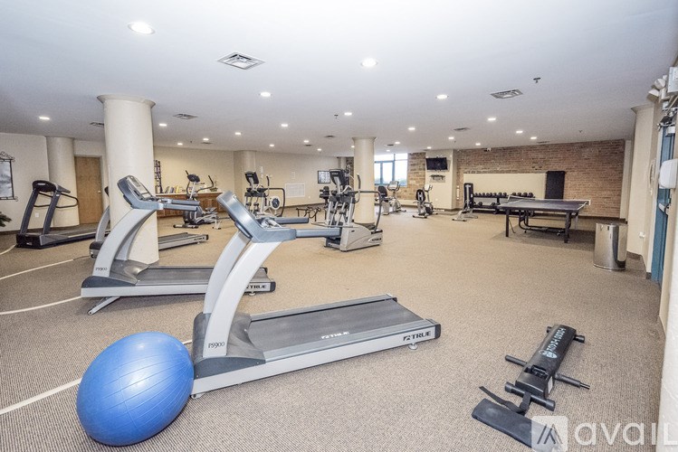 A gym with a variety of equipment including treadmills, weights, and a blue exercise ball.