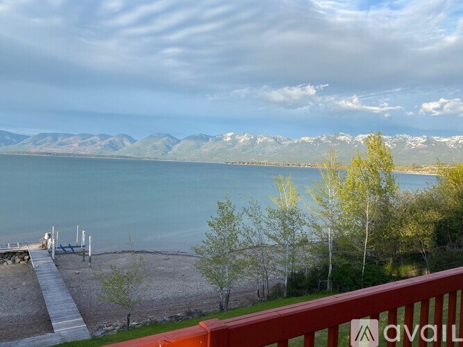 A view of a lake with mountains in the background and a wooden deck in the foreground.