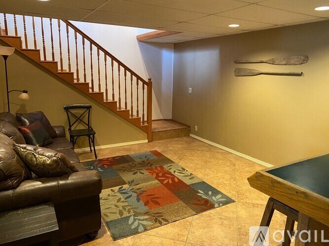 A living room with a brown leather couch, a wooden coffee table, and a rug with a floral pattern.