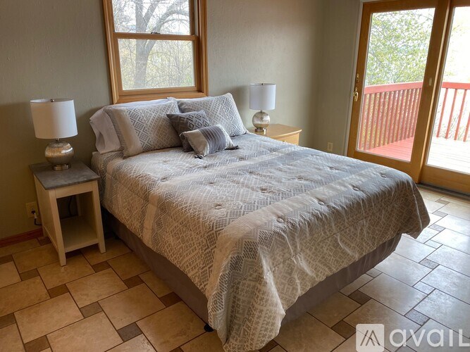 A bedroom with a large bed and a wooden nightstand with a lamp.