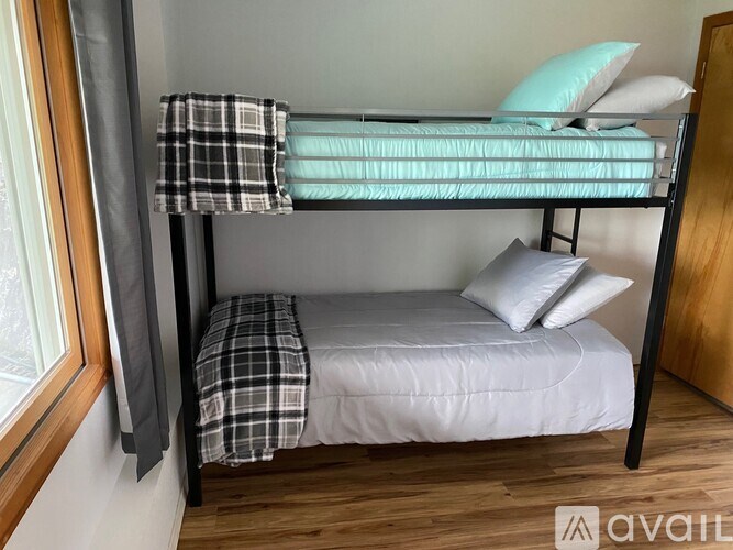 A bunk bed with a white mattress and a green pillow on top.