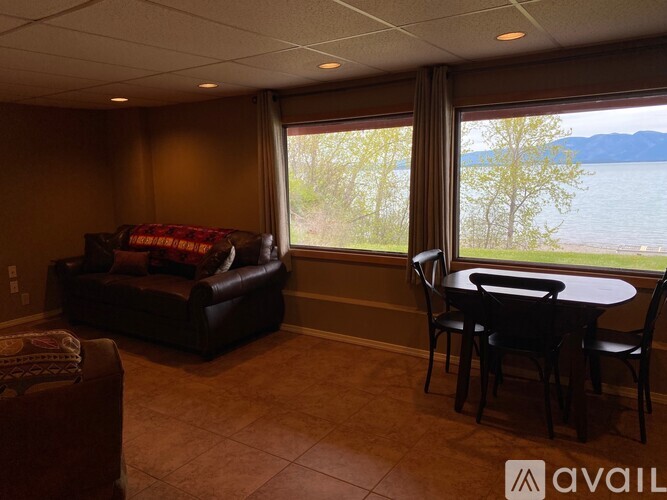 A living room with a couch, chair, and table with a view of a lake.