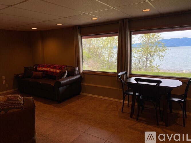 A living room with a couch, chair, and table with a view of a lake.