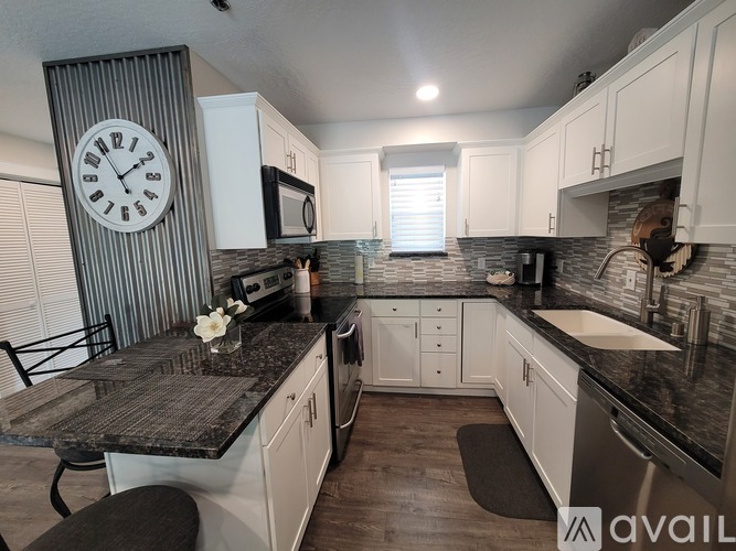 A kitchen with a black granite countertop and white cabinets.