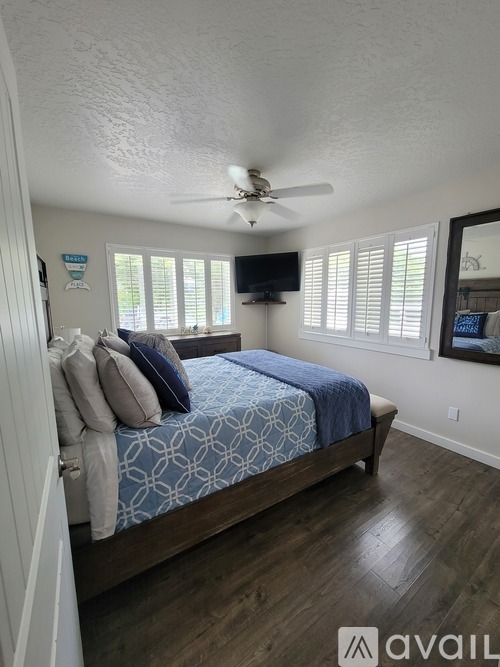 A bedroom with a bed, ceiling fan, and a window with blinds.