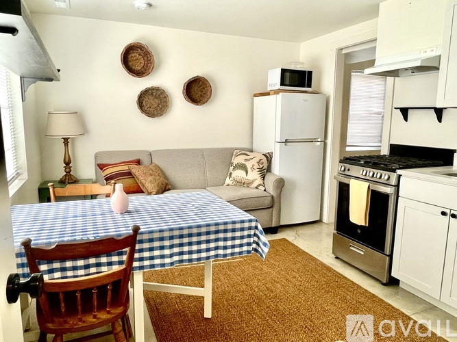 A living room with a white couch, a wooden table, and a window with curtains.