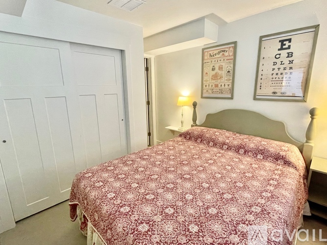 A bedroom with a bed covered in a red floral bedspread.