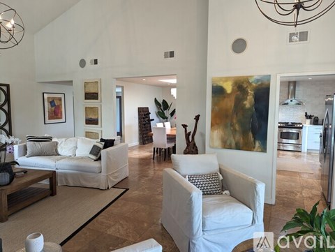 A living room with a white couch and a painting on the wall.