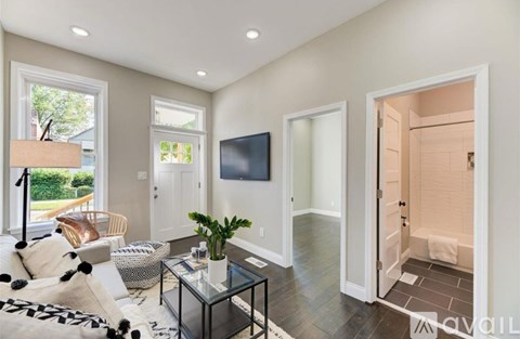 A living room with a glass coffee table and a flat screen TV on the wall.