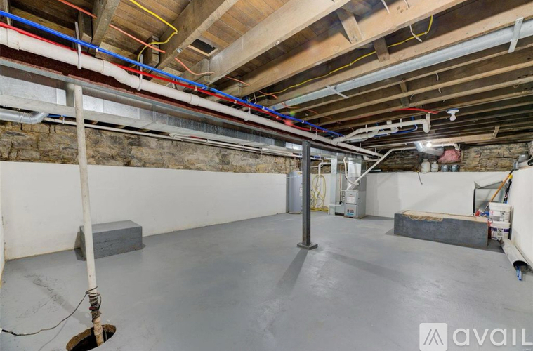A spacious basement with concrete floors and exposed ceiling beams.