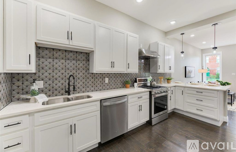 A modern kitchen with white cabinets and a grey backsplash.