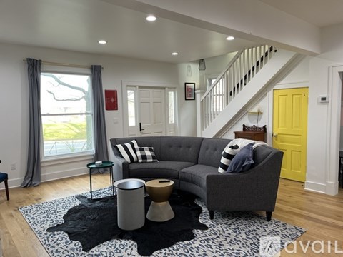 A living room with a grey couch and a yellow door.