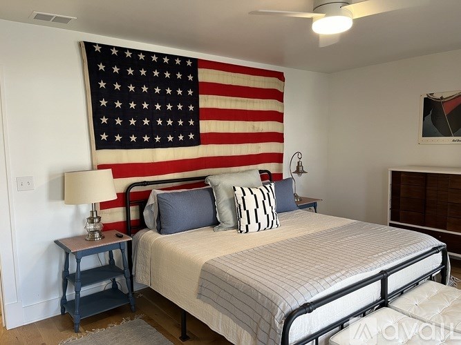 A bedroom with a large American flag on the wall.