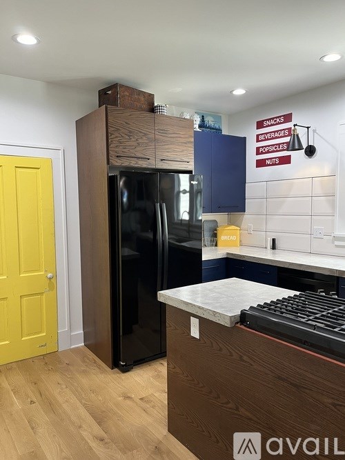 A kitchen with a yellow door and a black fridge.
