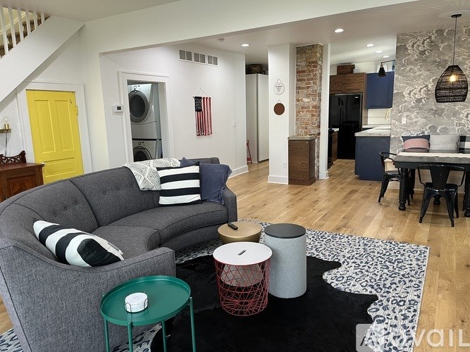 A living room with a grey couch and a yellow door.