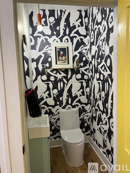 A bathroom with a toilet and a framed picture on the wall.