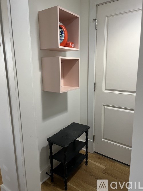 A small black stool is in front of a white door.