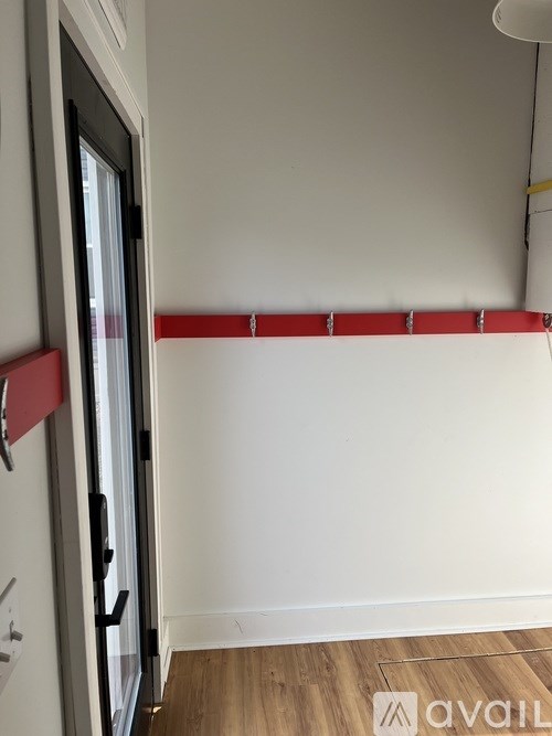 A white wall with a red stripe and a door.