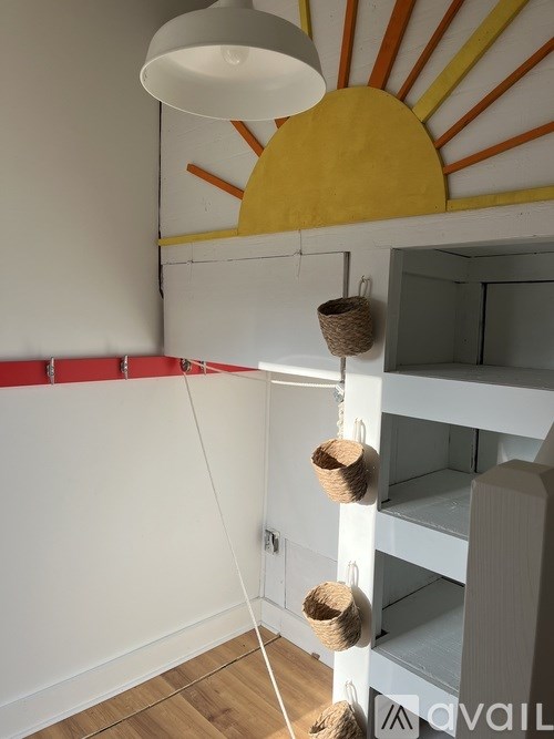 A white bunk bed with a yellow sun design on the wall above it.
