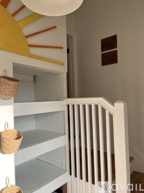 A white staircase with a white railing and a white wall with a yellow and orange painting.