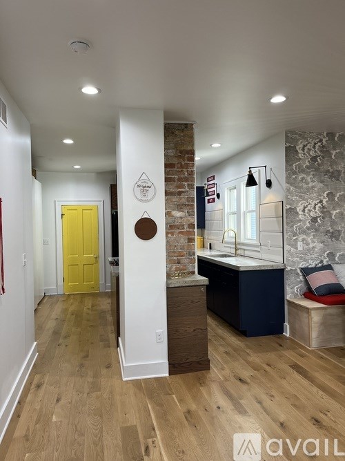 A hallway with a yellow door and a brick wall.