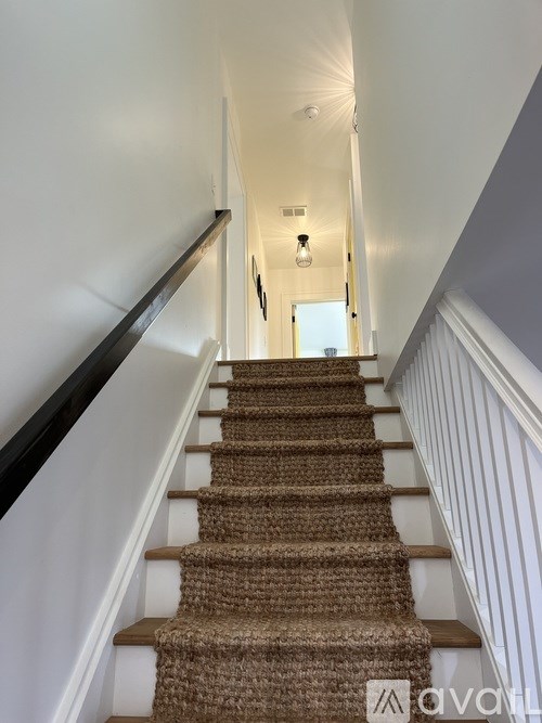 A staircase with a carpeted runner and white walls.