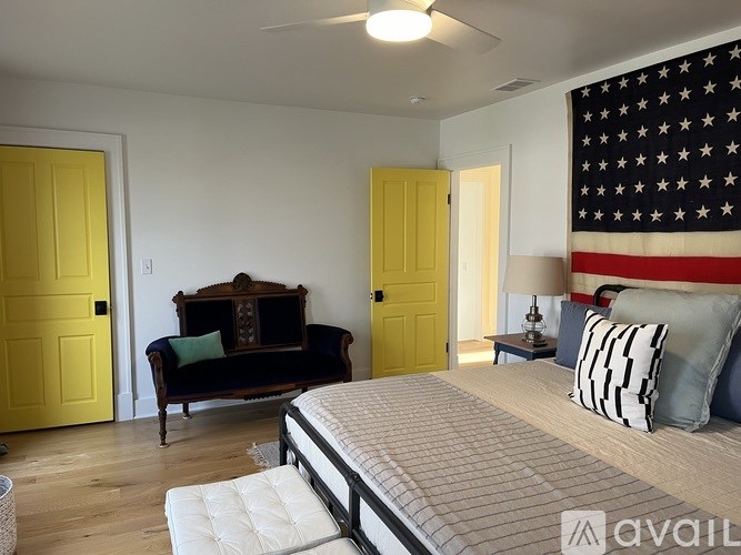 A bedroom with a bed, a sofa, and an American flag on the wall.