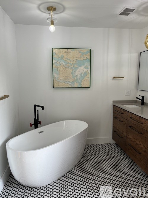 A white freestanding bathtub in a bathroom with a black and white floor.