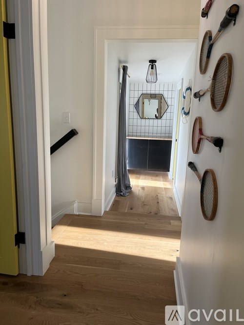 Tennis rackets are hung on the wall in a hallway.
