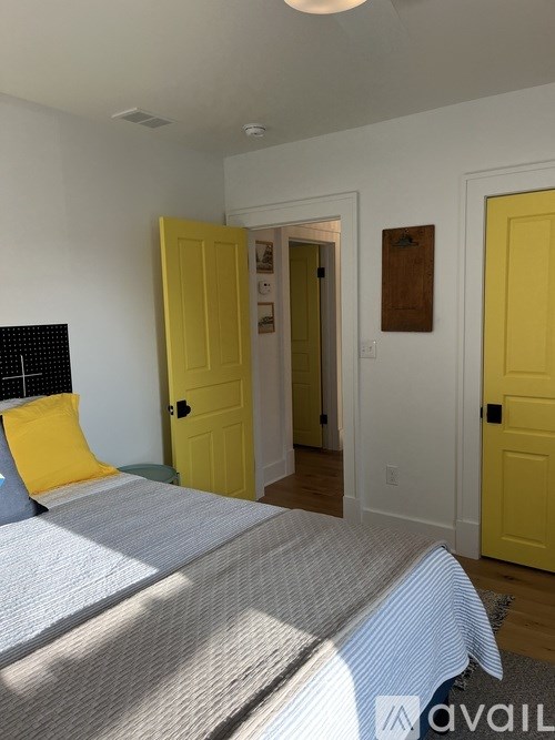 A bedroom with a bed, two yellow doors, and a white wall.