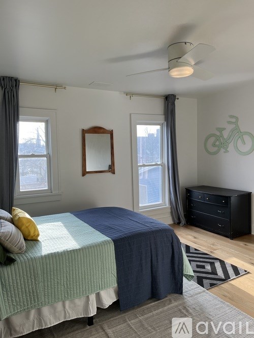 A bedroom with a bed, dresser, mirror, and a bicycle decal on the wall.