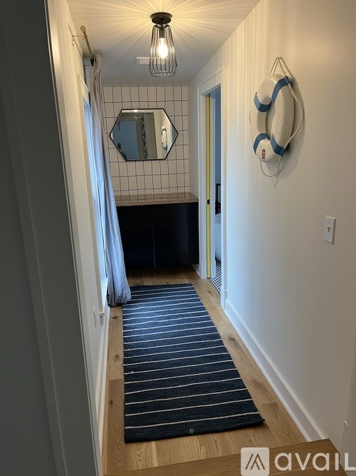 A hallway with a striped rug and a mirror on the wall.