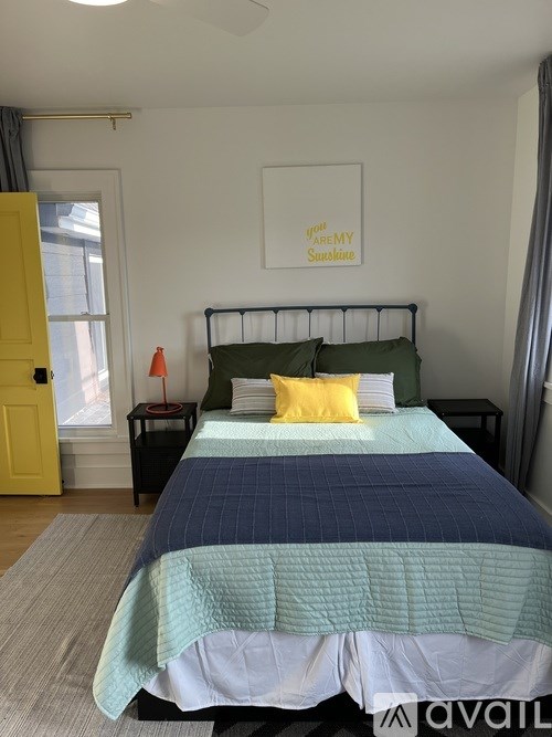 A bedroom with a bed, a nightstand, and a framed picture on the wall.