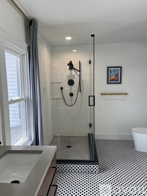 A bathroom with a black and white floor, a white toilet, a sink, and a shower with a glass door.