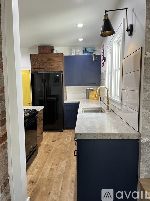 A kitchen with a black fridge and wooden cabinets.