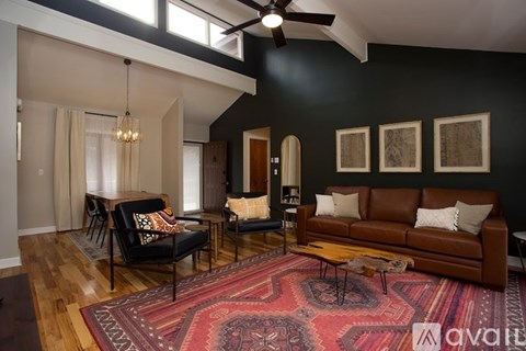 A living room with a rug on the floor and a ceiling fan above.