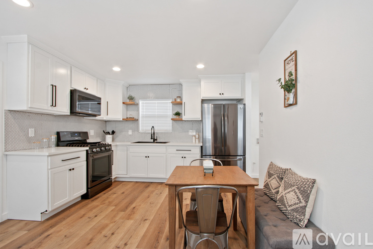 A kitchen with white cabinets and a wooden table.