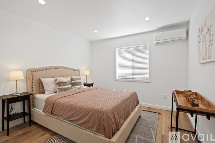 A bedroom with a large bed and a nightstand with a lamp.