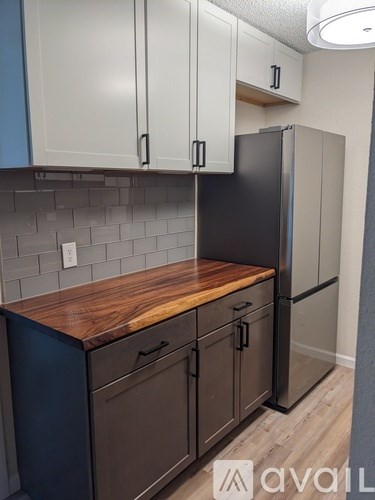 A kitchen with a black refrigerator and wooden countertop.