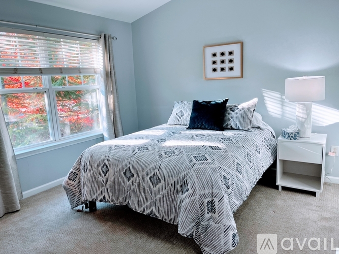 A bedroom with a bed, nightstand, and window with blinds.