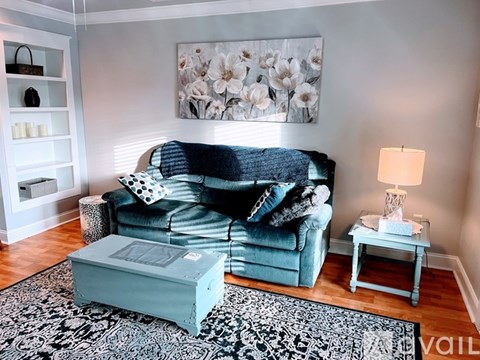 A living room with a blue couch and a grey ottoman.