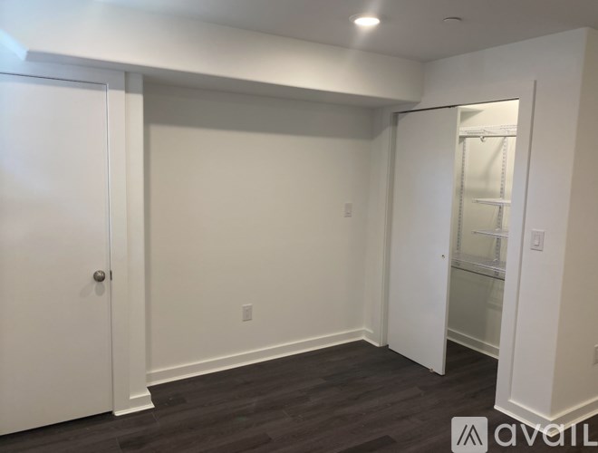 A white door is open to a room with a white wall and a white closet.