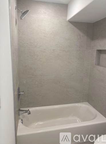 A white bathtub with a shower head attached to the wall.