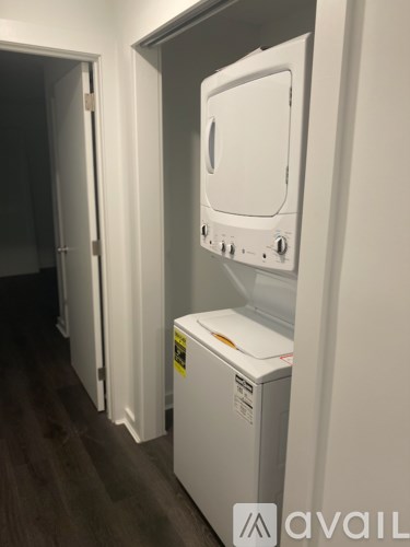 A white dryer is in a narrow hallway.