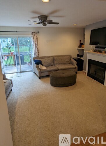 A living room with a grey couch and a fan on the ceiling.