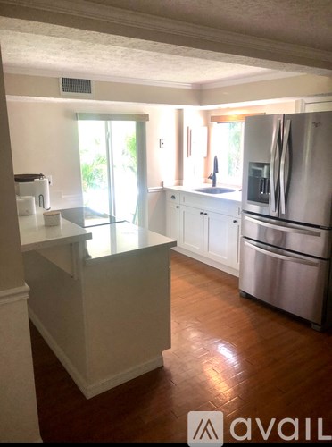 A kitchen with white cabinets and a stainless steel refrigerator.