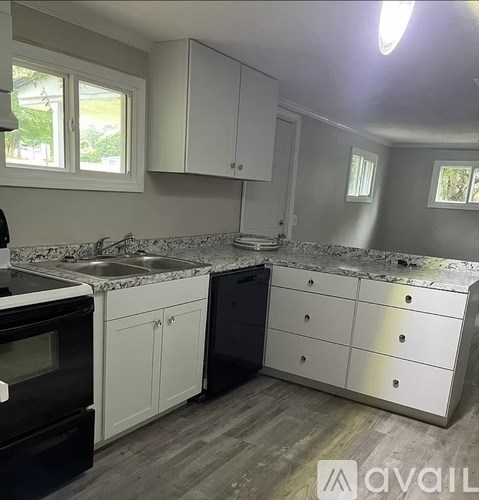 A kitchen with a black dishwasher and white cabinets.