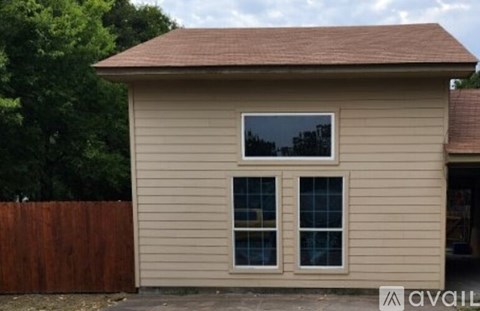 A small house with a brown roof and a brown fence.