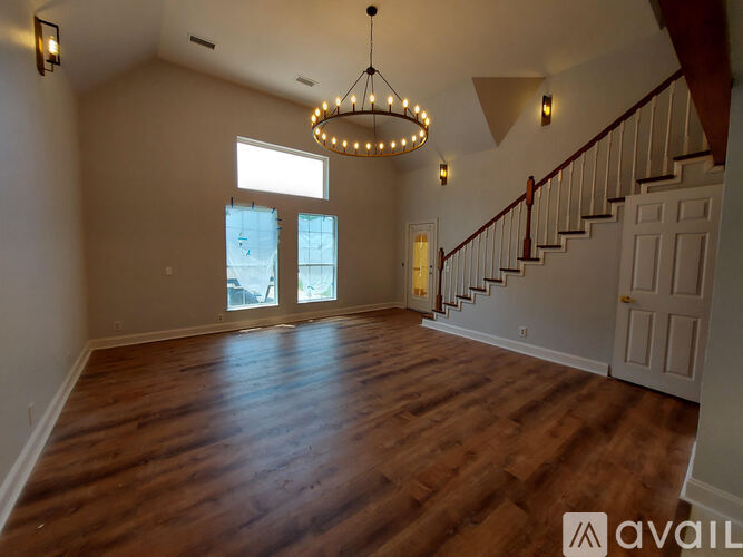 A large, empty room with wooden floors and a staircase leading to the second floor.